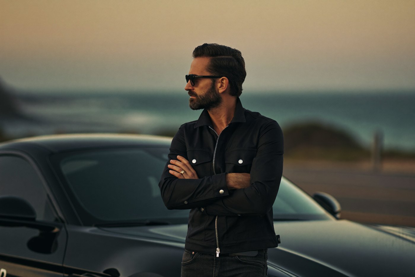 A confident Tuffs client leaning on his car at the coast